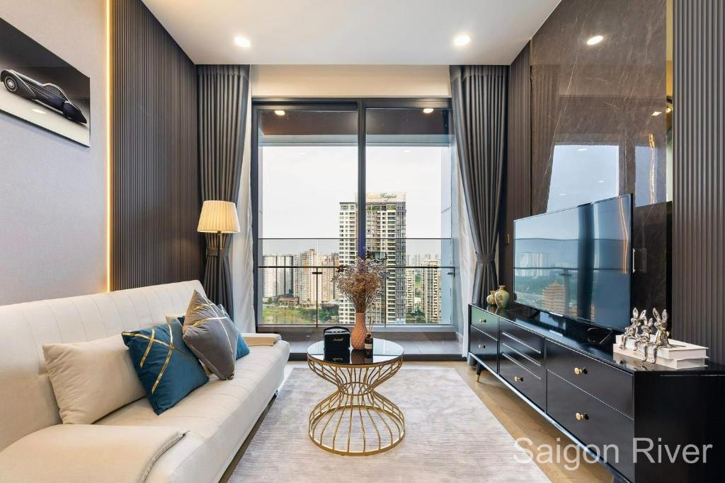 uma sala de estar com um sofá branco e uma televisão grande em Lume Metro Saigon River em Cidade de Ho Chi Minh