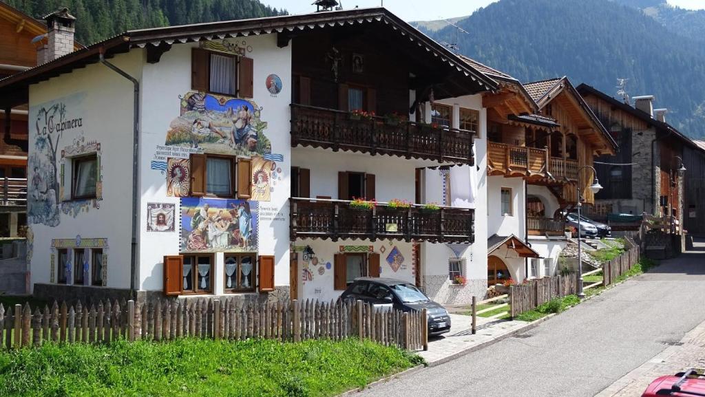 a white building with paintings on the side of it at La Capinera Canazei Apartments in Canazei