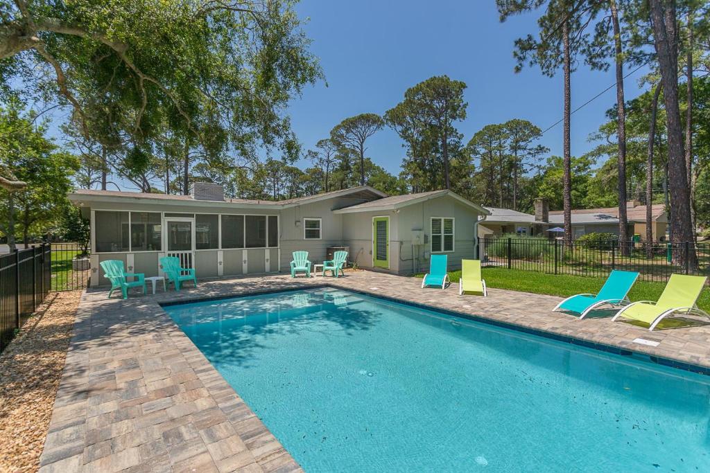 a swimming pool with chairs and a house at Sweetpeas Cottage in Jekyll Island