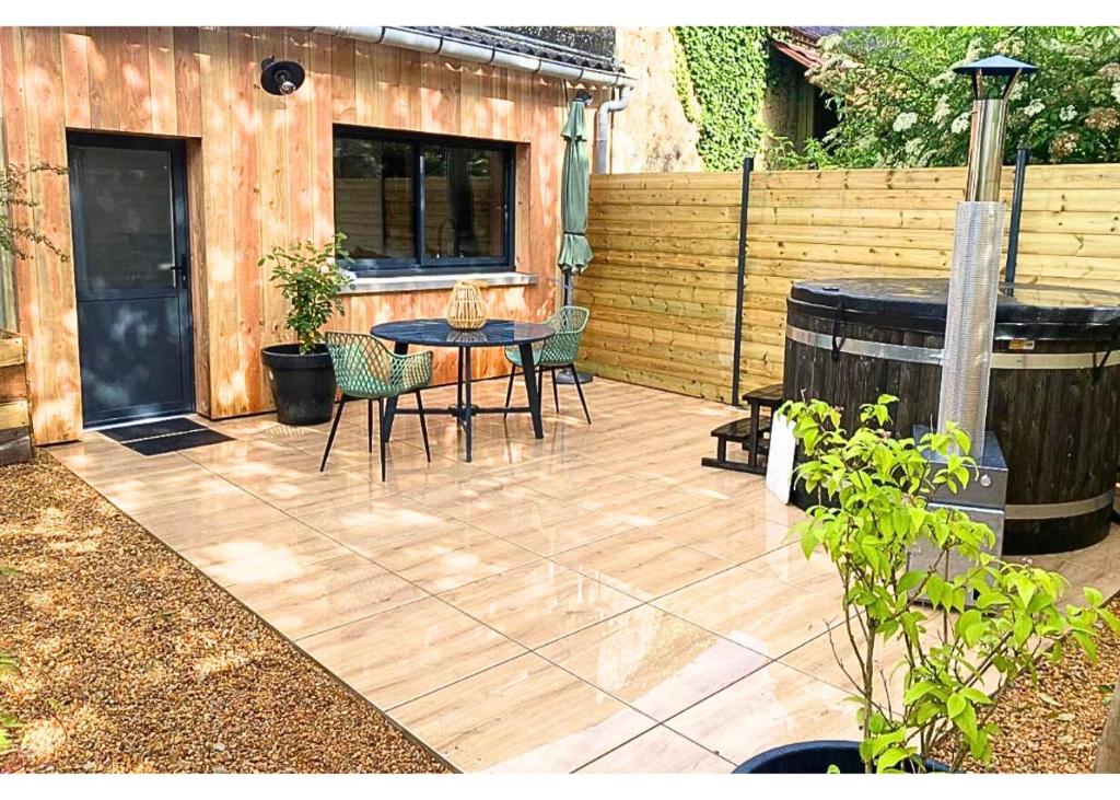 a patio with a table and chairs and a barrel at Chalet bain nordique - Calm & relax in Bellême
