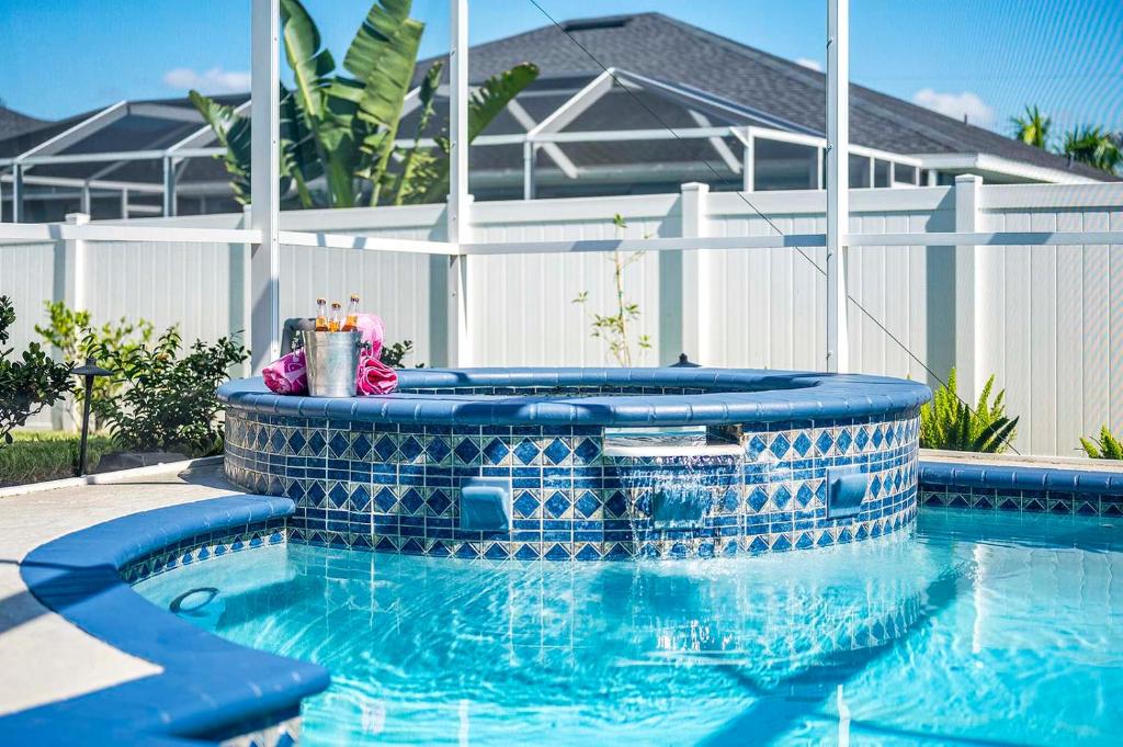 ein Swimmingpool mit einer blau gefliesten Badewanne neben einem Haus in der Unterkunft Endless Summer - 4 Bedroom with Gym and Jacuzzi in Matlacha