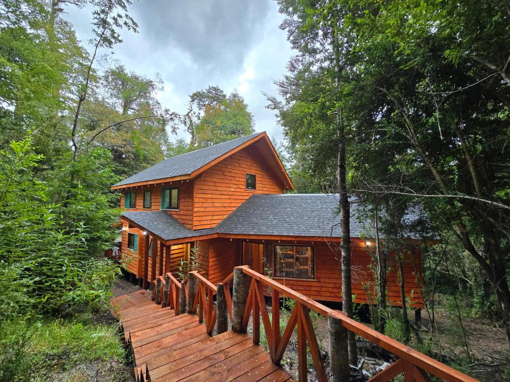 une cabane en rondins dans les bois avec une passerelle en bois dans l'établissement Casa Mágica en Bosque Huilo Huilo, à Neltume