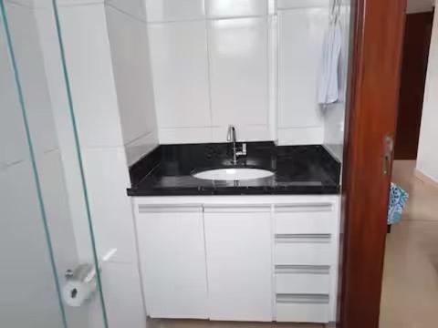a white bathroom with a sink and a shower at Casa de Carolinda in Uberaba