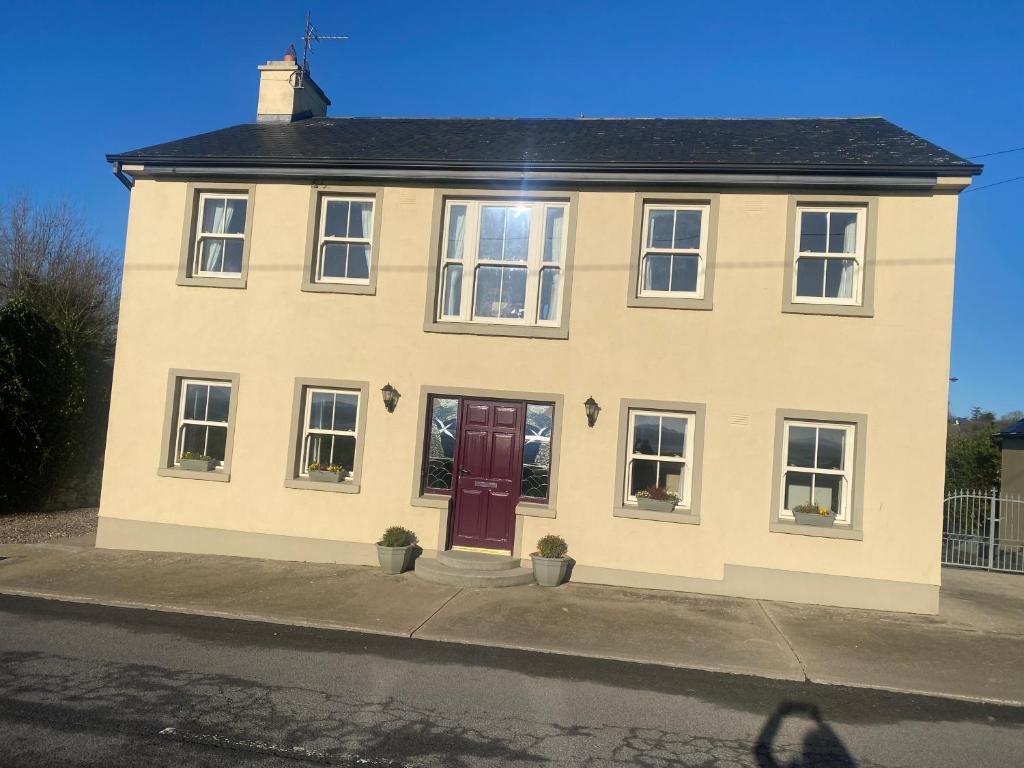 a white house with a red door on a street at scenic estuary way home in Labasheeda