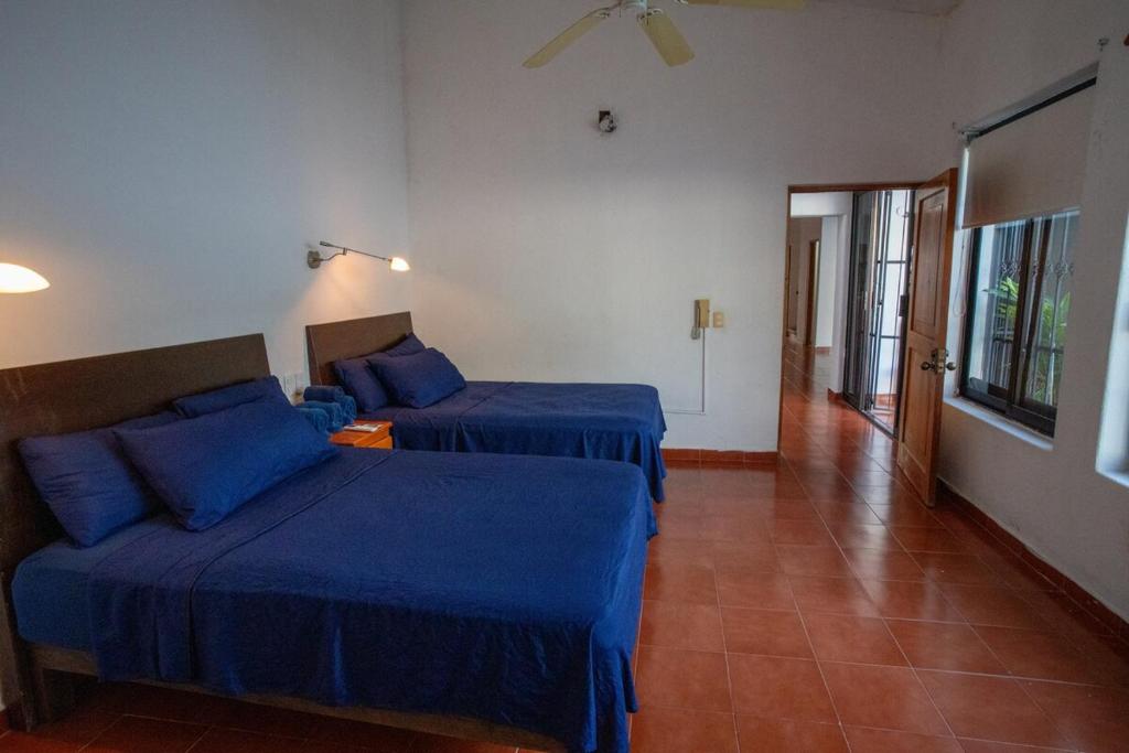 two beds in a hotel room with blue sheets at Casa Rubí comfortable and with a private pool in Zihuatanejo