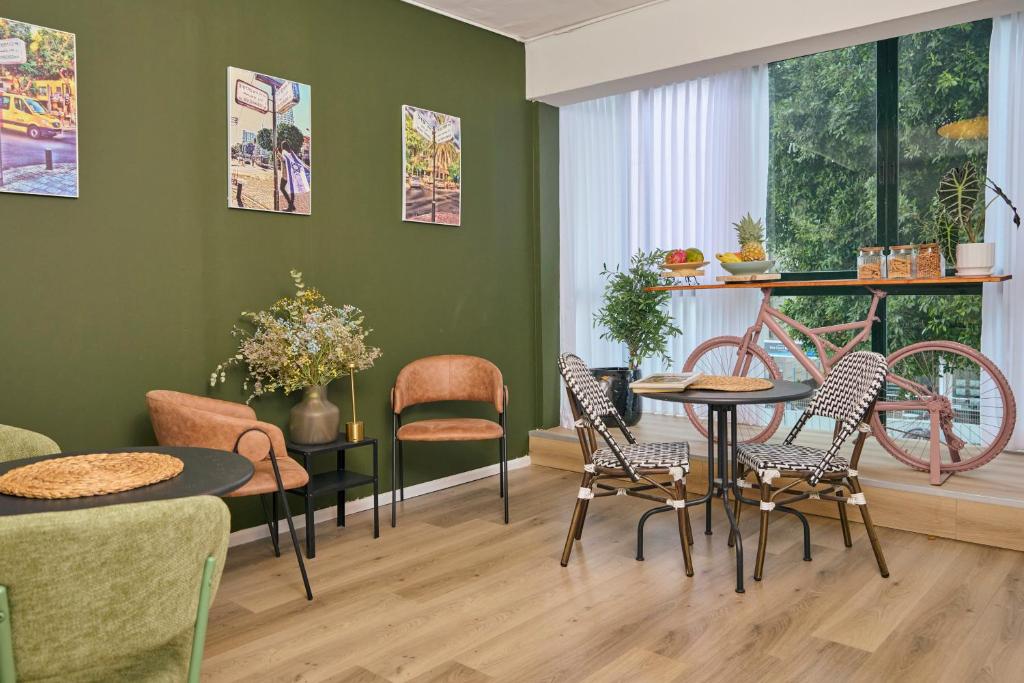 a living room with green walls and a table and chairs at H7 TLV in Tel Aviv