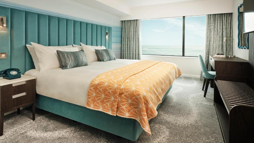 a bedroom with a large bed and a large window at Hotel Indigo Torquay, By IHG in Torquay