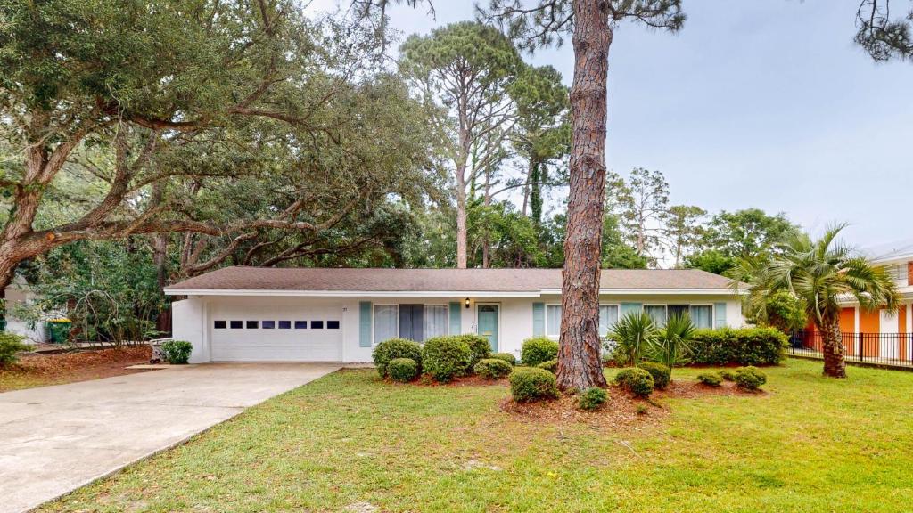 a white house with a tree and a driveway at Reflection in Jekyll Island