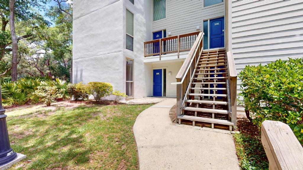 a house with a staircase in front of a yard at Villa 326 - A SHORE THING in Jekyll Island