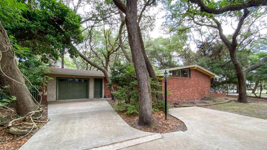 a brick house with a garage and trees at Very Nice Cottage in Jekyll Island