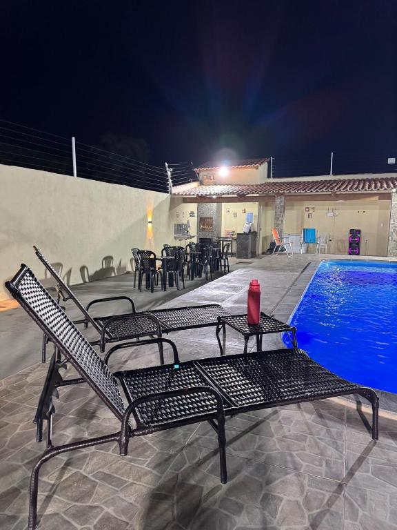 a table and chairs next to a swimming pool at night at Espaço para Eventos e Temporadas em in Paracuru
