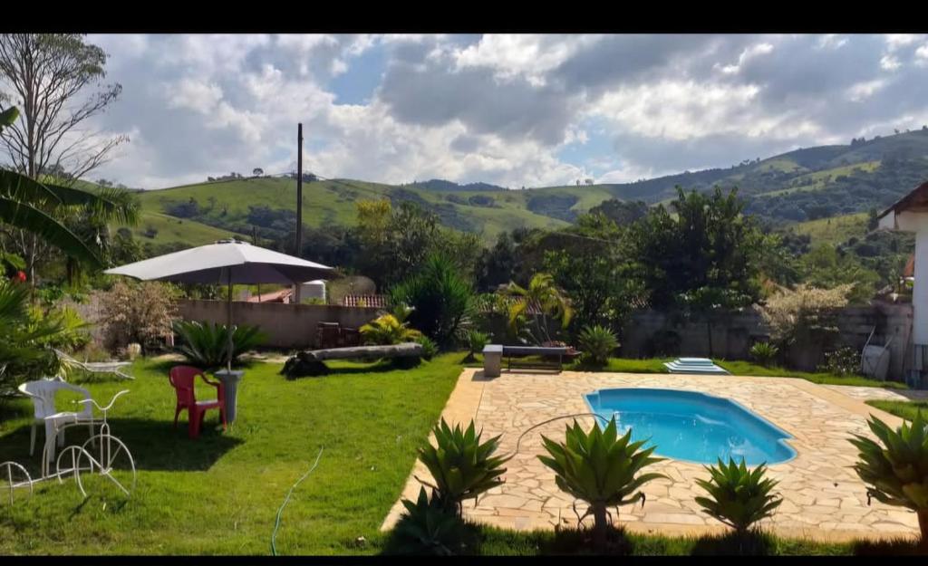 a backyard with a swimming pool and an umbrella at Chácara maravilha in Monte Sião