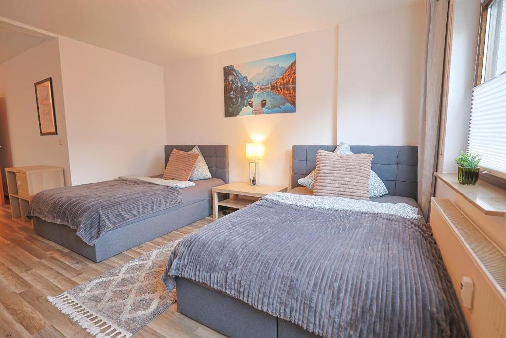 Ferienwohnung in Lohfelden nahe Kassel في لوهْفيلدِن: غرفة نوم بها سريرين وطاولة مع مصباح