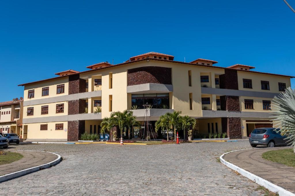 a large building with palm trees in front of it at Apartamento Resort Cabo Frio - Rua dos Biquinis in Cabo Frio