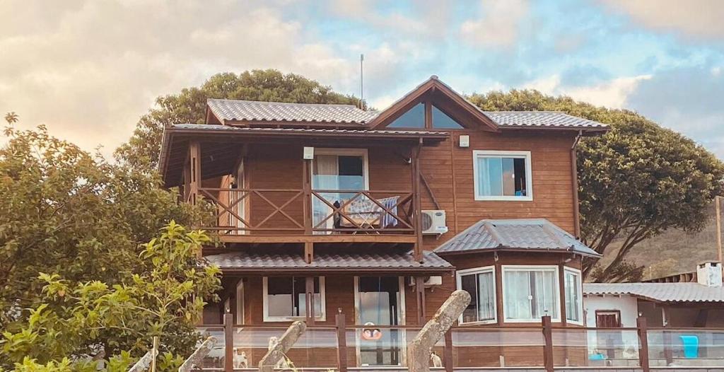 a wooden house with a balcony on top of it at Casa com piscina a 300m praia in Imbituba