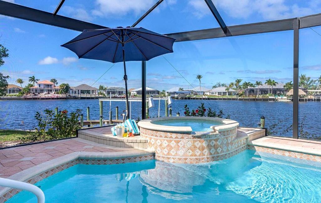 ein Pool mit einem Sonnenschirm neben dem Wasser in der Unterkunft Palm Pointe - Waterfront Vacation Rental Cape Cora in Matlacha