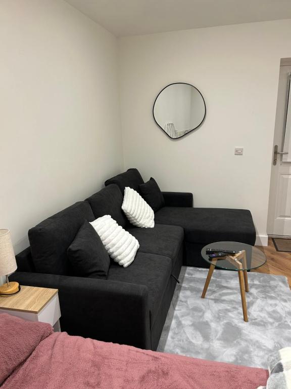 a living room with a black couch and a mirror at Cosy Corner Cheadle in Cheadle
