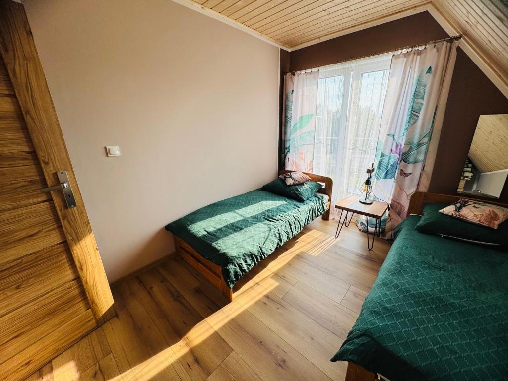 a room with two beds and a window at Zajazd Jędruś - Domki Całoroczne in Idzików