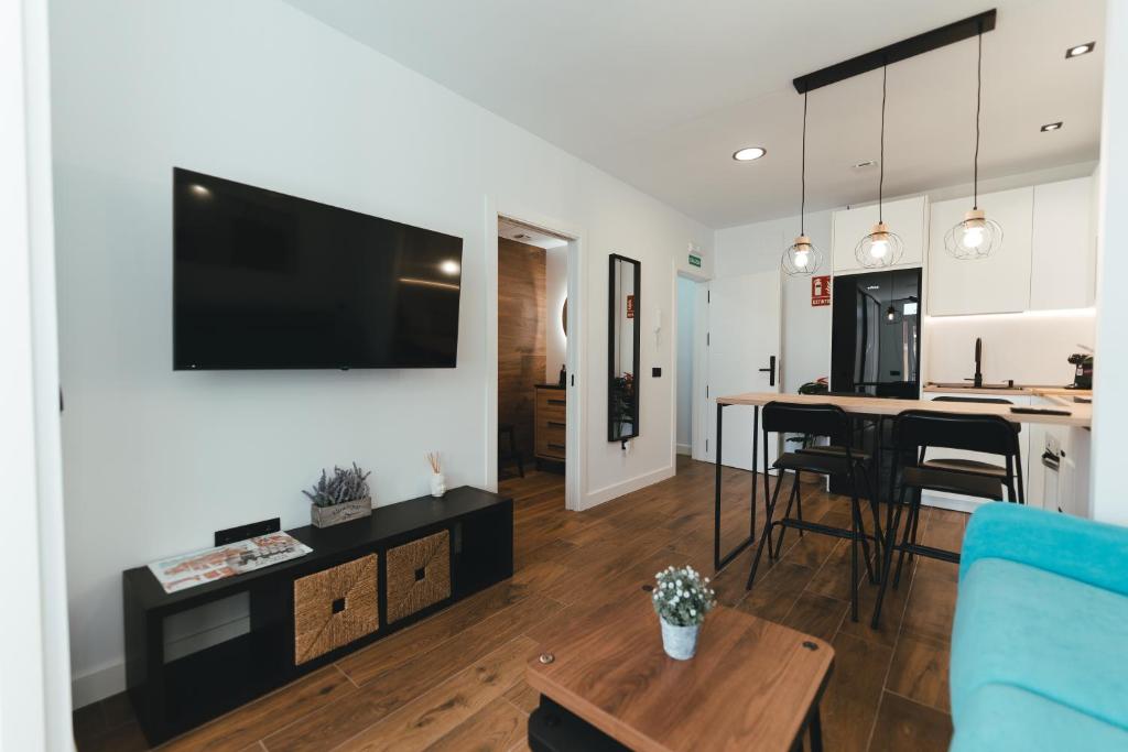 sala de estar y cocina con TV de pantalla plana. en Macarena Suites, en Cáceres