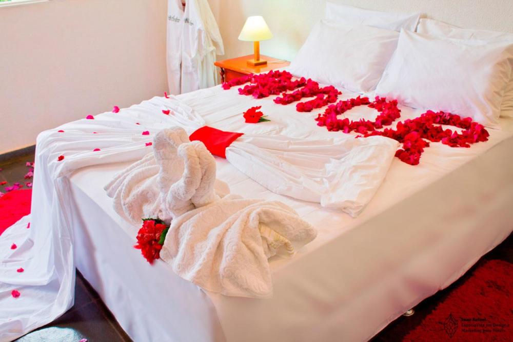 马普托Night House的一张白色的床,上面有红色的鲜花