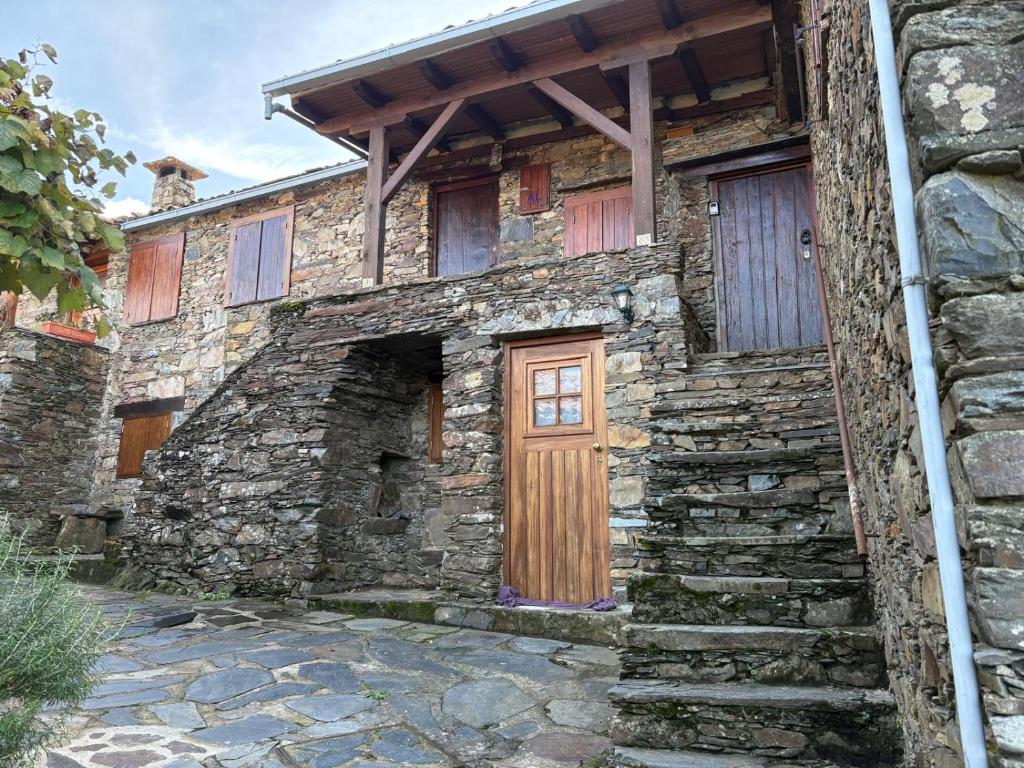 a stone house with a wooden door and stairs at Casas do Caminho in Lousã