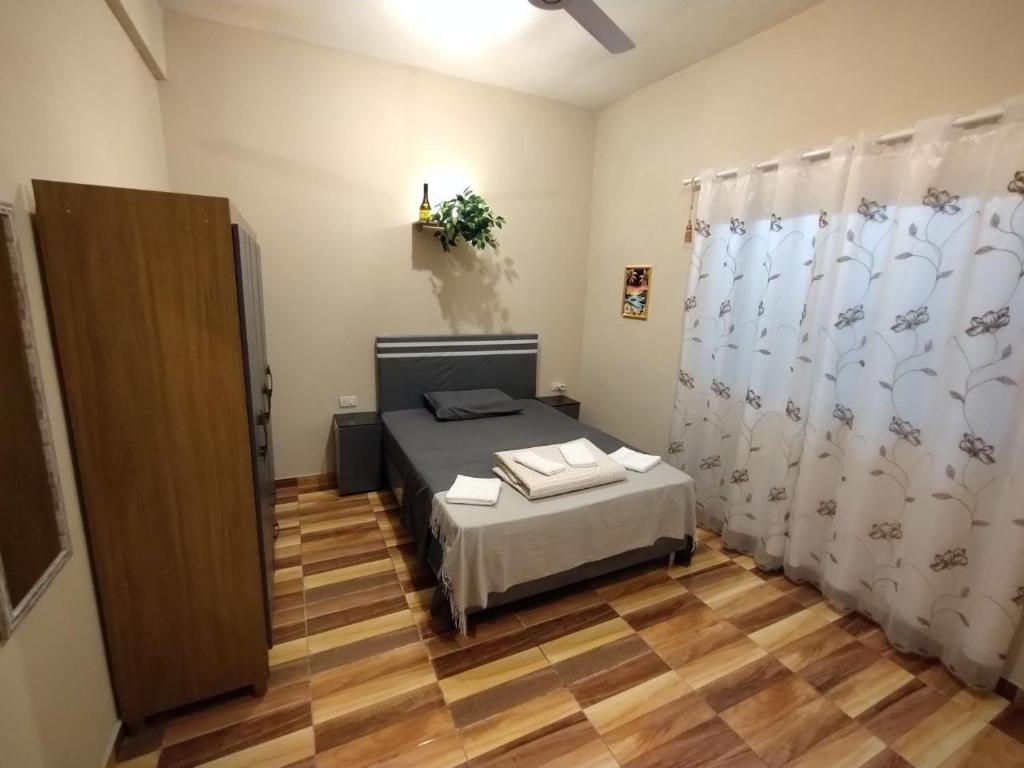 1 dormitorio con cama, cortinas y suelo de madera en Prisma21, en Luque