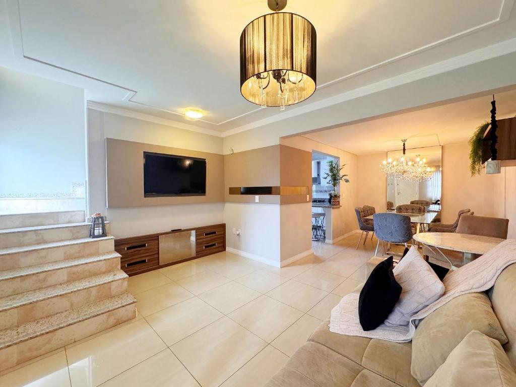 a living room with a couch and a dining room at Casa moderna e extremamente confortável - R1552 in Balneário Camboriú