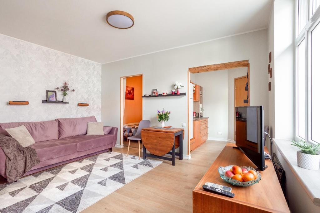 a living room with a purple couch and a tv at Old town apartment in Pärnu