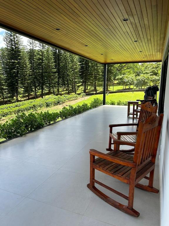 two wooden rocking chairs on a porch with a view of a park at Casa Arara in Espirito Santo Do Pinhal
