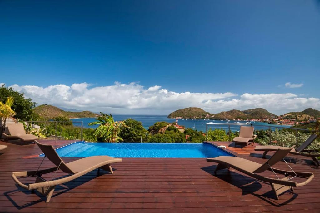 a pool with chairs and a view of the ocean at Villa Mangouste in Terre-de-Haut