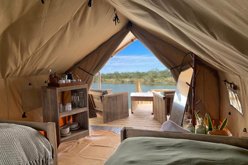 a tent with a bed and a view of the water at Glamping Escape Safari Tent Near SpaceX in Colonia Acres