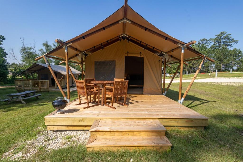 a tent with a table and chairs in a field at A Calm and Cozy Lakeside Glamping Retreat Awaits in Onalaska