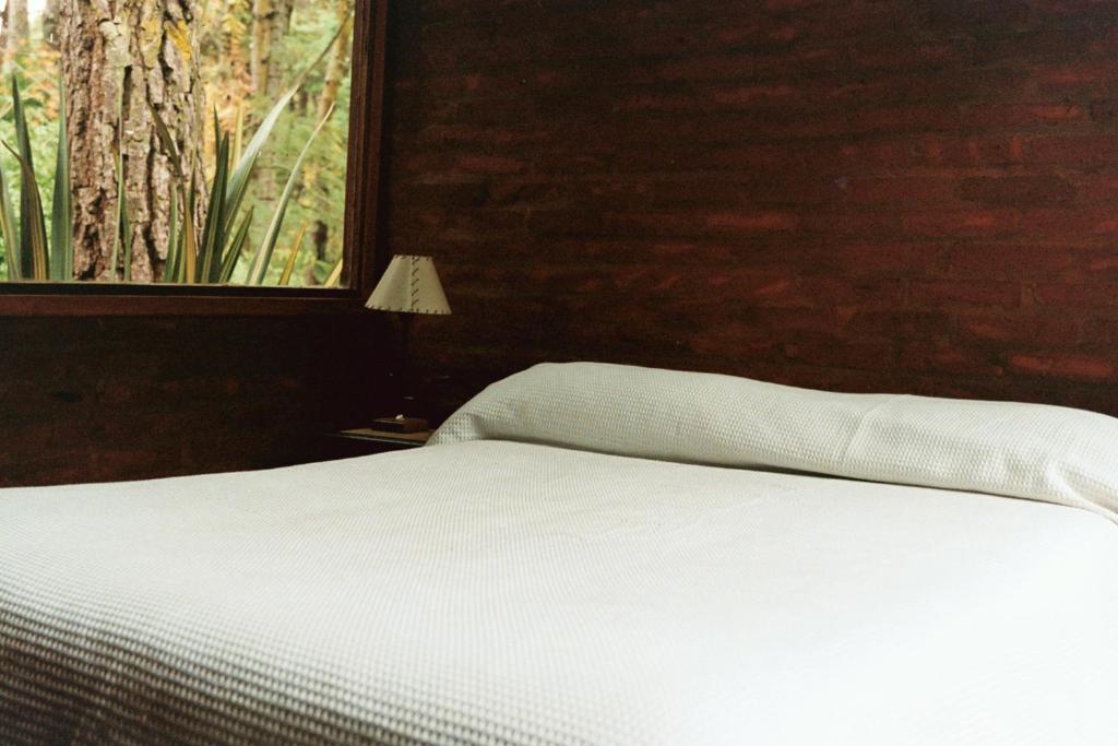 una camera da letto con un letto bianco e una finestra di Cabaña Ceibo a Mar de las Pampas