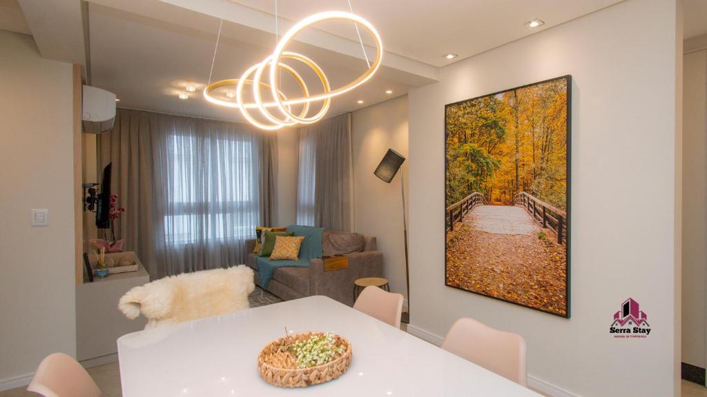 a living room with a table and a painting on the wall at Apartamento Luxo em Bento Gonçalves in Bento Gonçalves