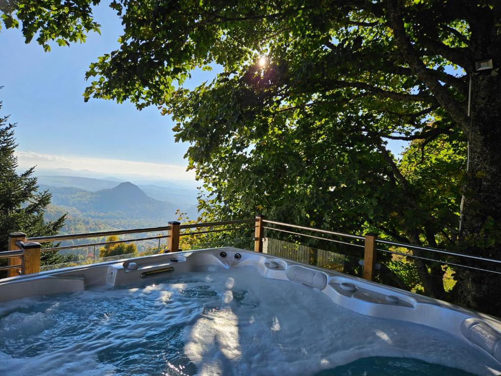 a hot tub with a view of the mountains at 3 Chalets avec vue imprenable et SPA in Queyrières