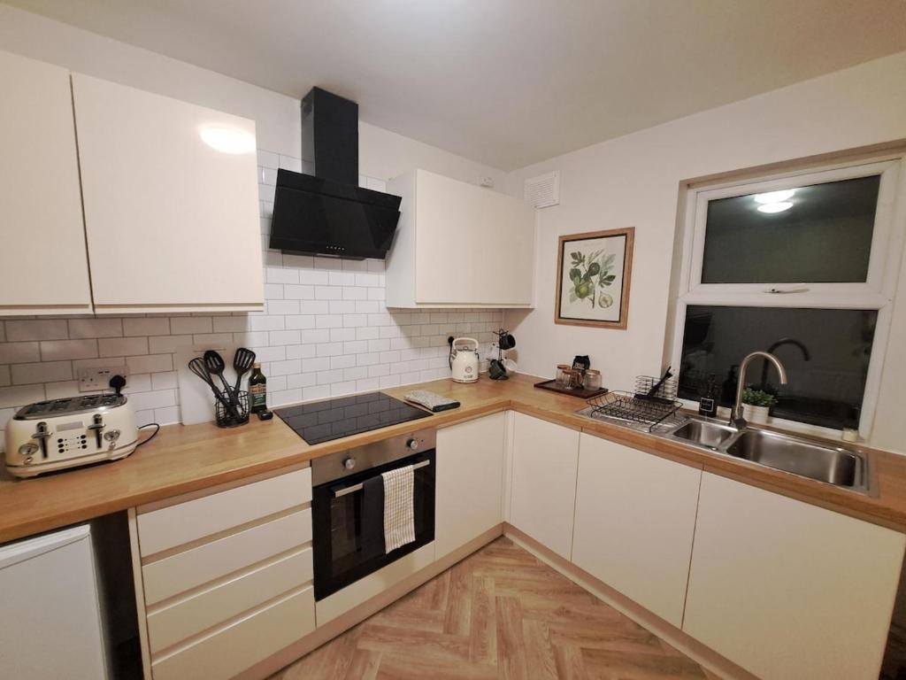 eine Küche mit weißen Schränken und einer Spüle in der Unterkunft Central Park View - Modern & Stylish 2 Bed Apartment - Great Location in Scunthorpe