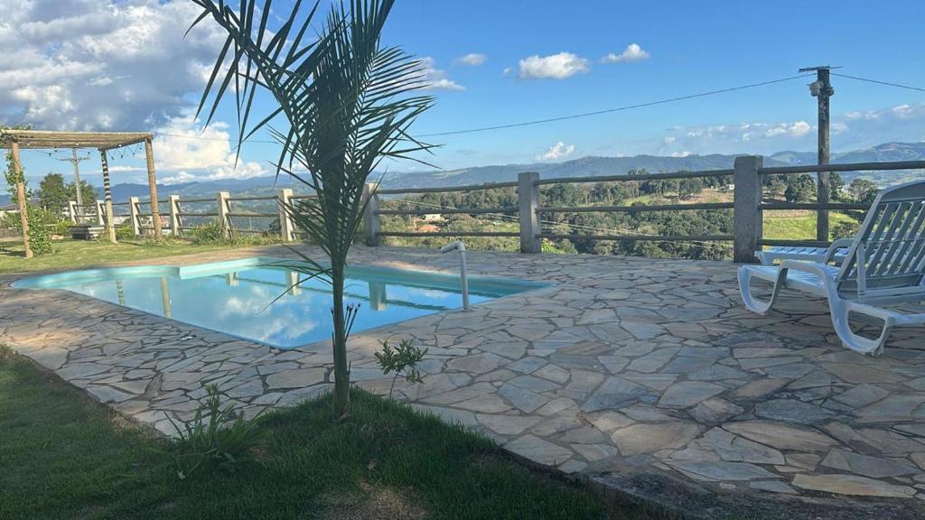 un palmier et une chaise à côté d'une piscine dans l'établissement Pousada Da Montanha, à Extrema