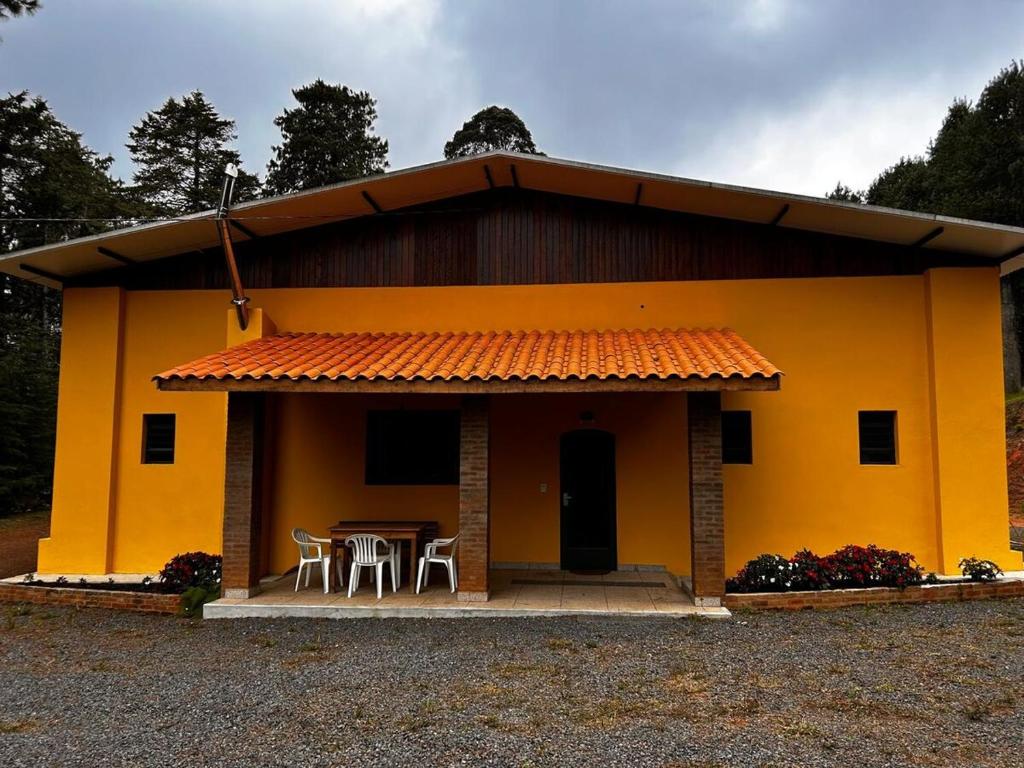 a small yellow house with a table and chairs at Casa Aquarius in Camanducaia