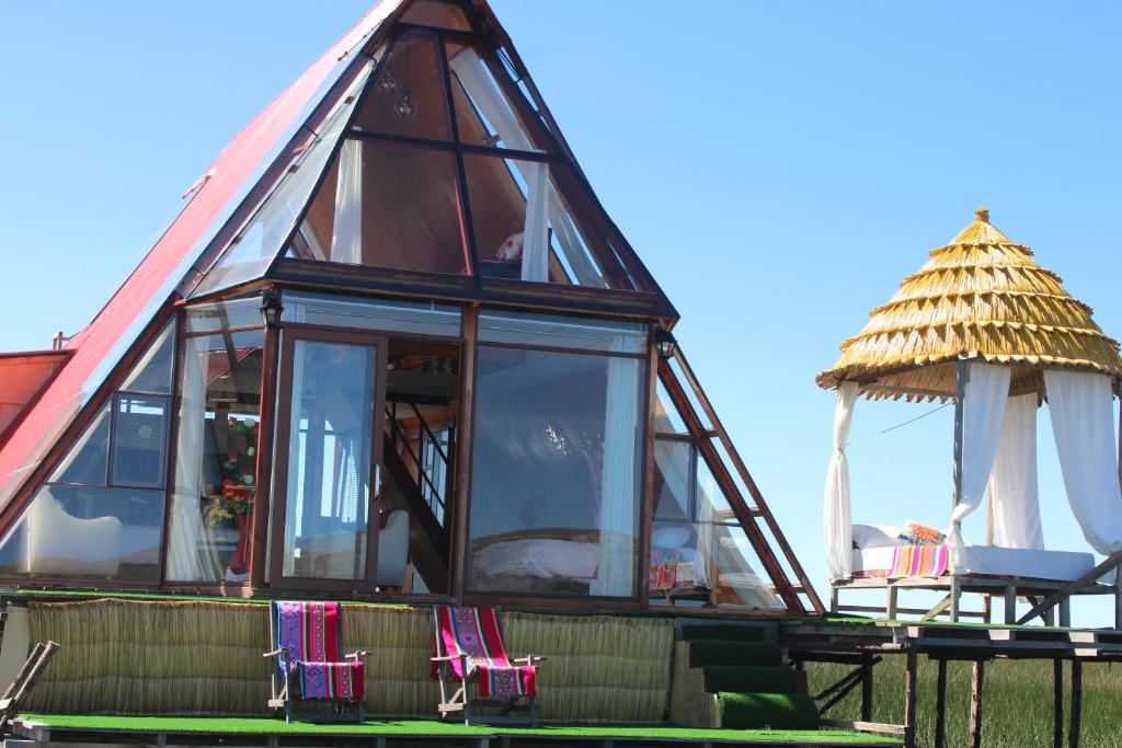 a house with a thatched roof and chairs at Titicaca SUMA SARTIRI in Puno