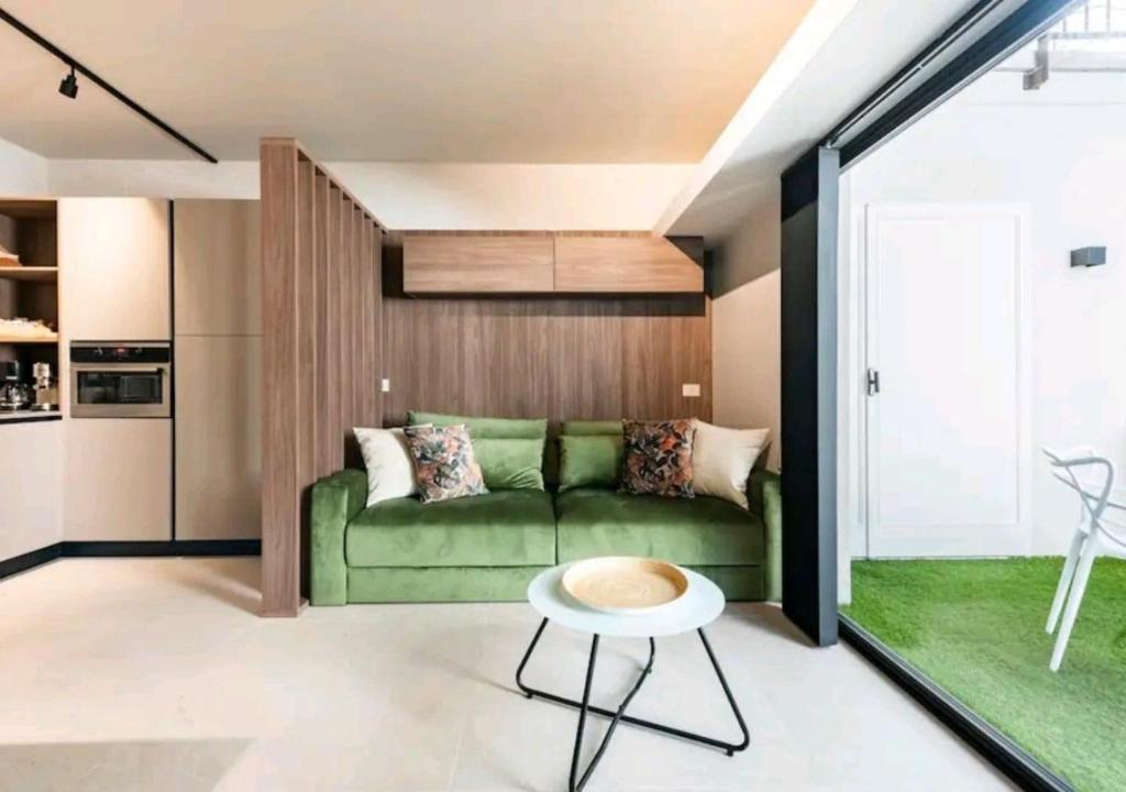 a living room with a green couch and a table at LagoC0C00N - Colazione - 300m stazione - 800m lago in Desenzano del Garda