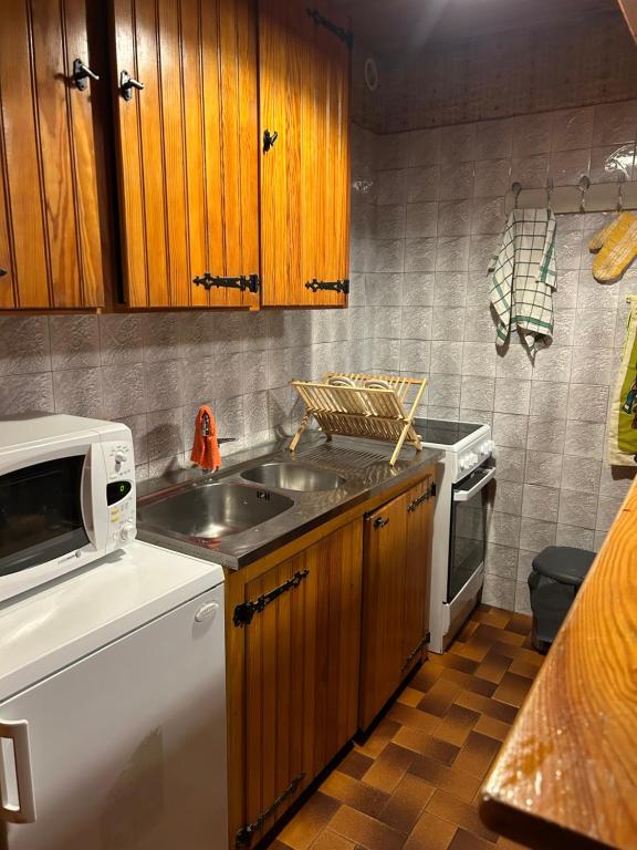 eine Küche mit Spüle und Mikrowelle in der Unterkunft Appartement au pied des pistes in Forest des Baniols