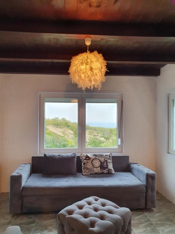 a living room with a couch and two windows at Pure nature lovely view house in Zaklopača