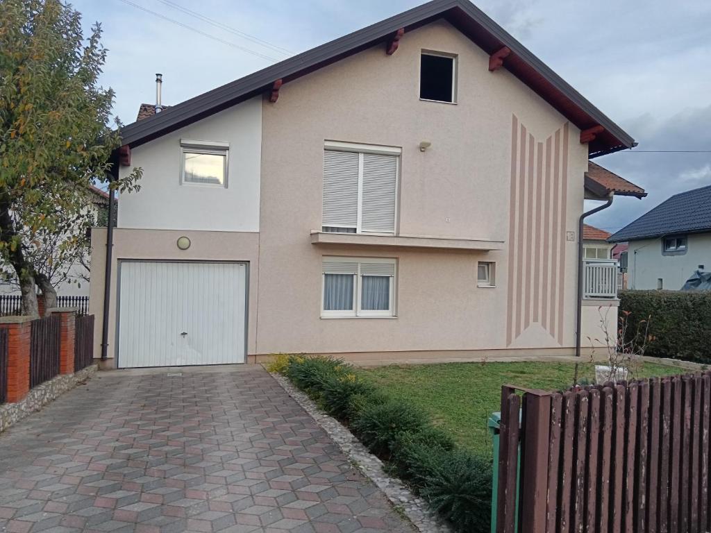una casa con garaje blanco y entrada de ladrillo en Apartmani Srebrenik, en Srebrenik