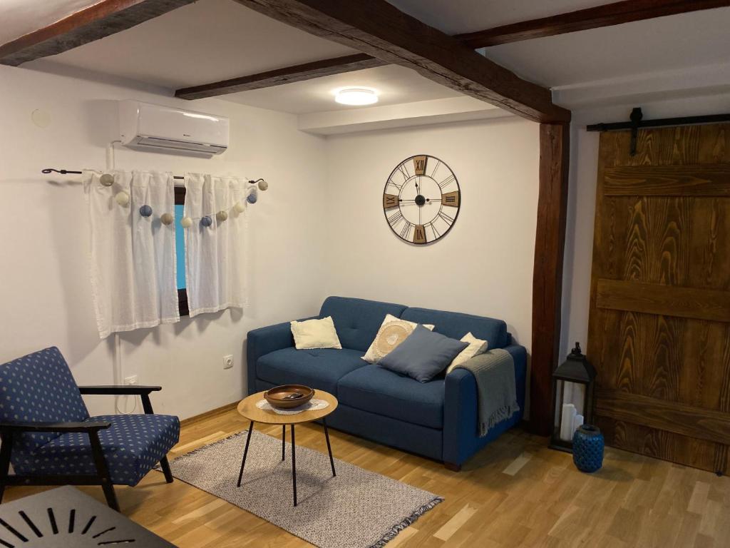 a living room with a blue couch and a clock at Kućice za odmor Šalatin jarek - Free tickets to local attractions in Ðurđevac