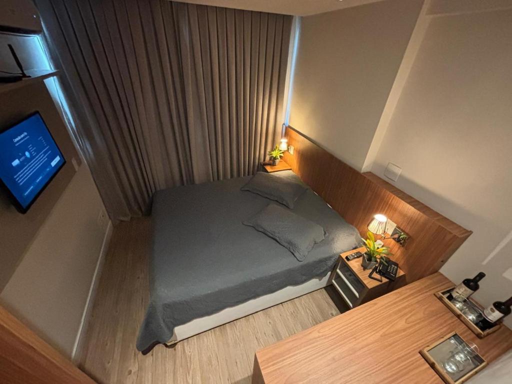 a small bedroom with a bed and a television at Transamérica Executive Campos dos Goytacazes in Campos dos Goytacazes