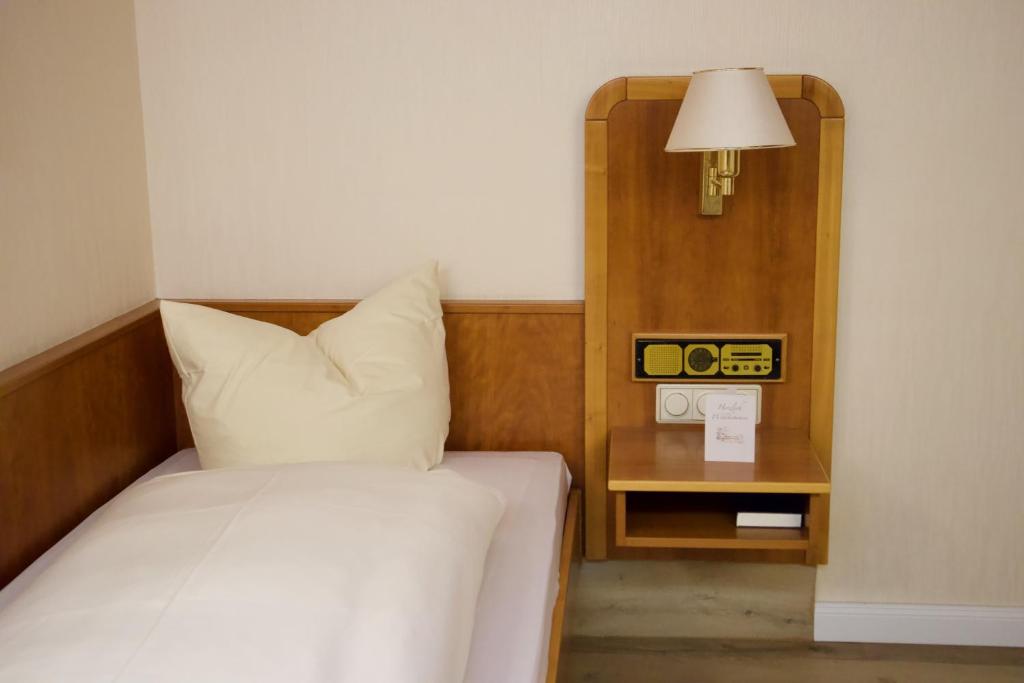 a bedroom with a bed with a lamp and a side table at Gästehaus Wild Nürnberg-West in Oberasbach