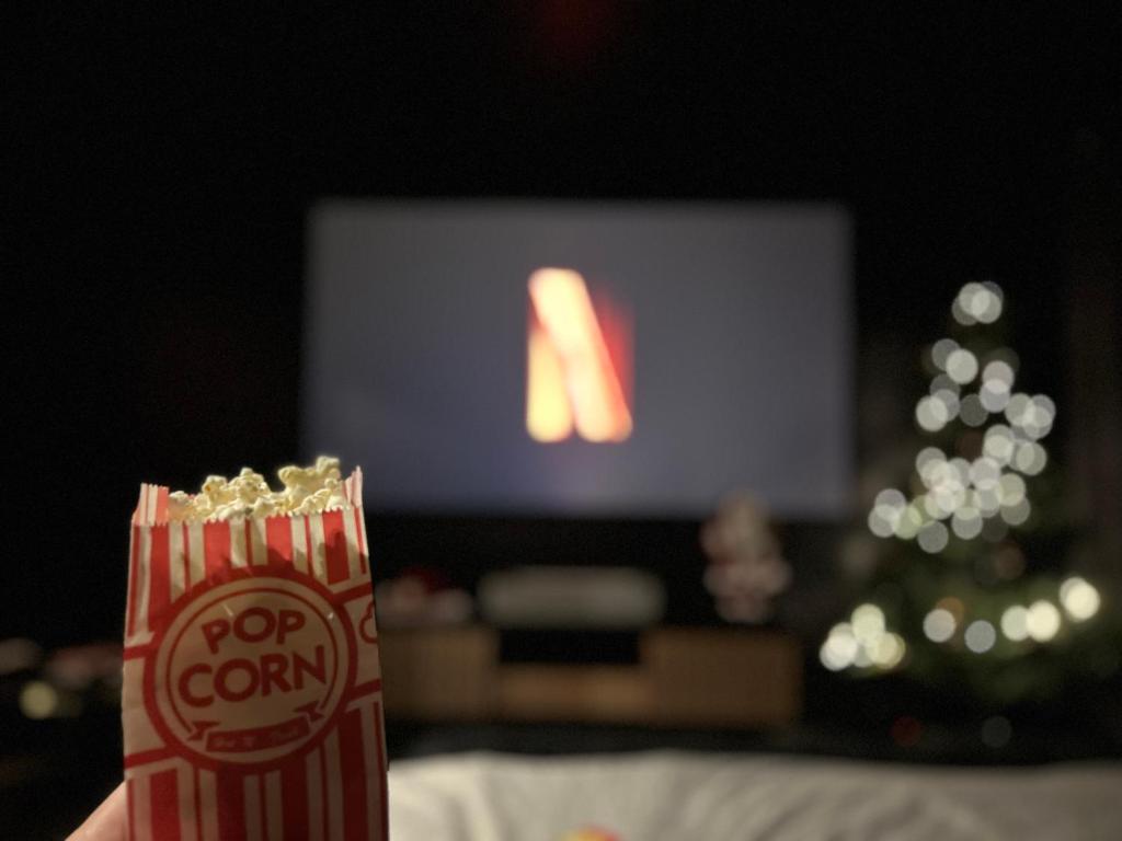 a person holding a popcorn bag in front of a television at Le parrain Expérience cinéma unique à Chartres in Chartres