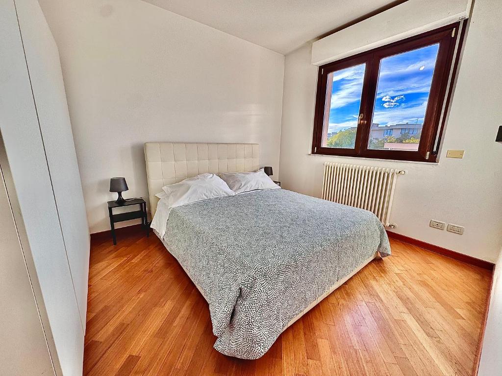 een witte slaapkamer met een bed en een raam bij Appartamento con posto auto riservato tra spiaggia, centro, stazione ed ospedale in Pescara