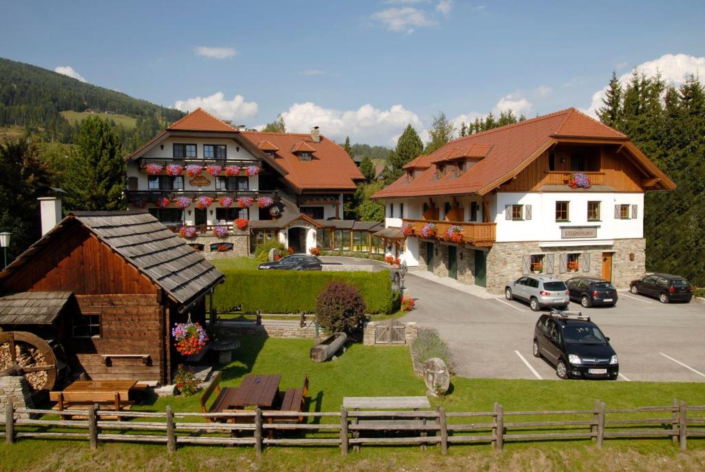 a group of buildings and a parking lot with cars at Hotel Stegmühlhof in Mauterndorf