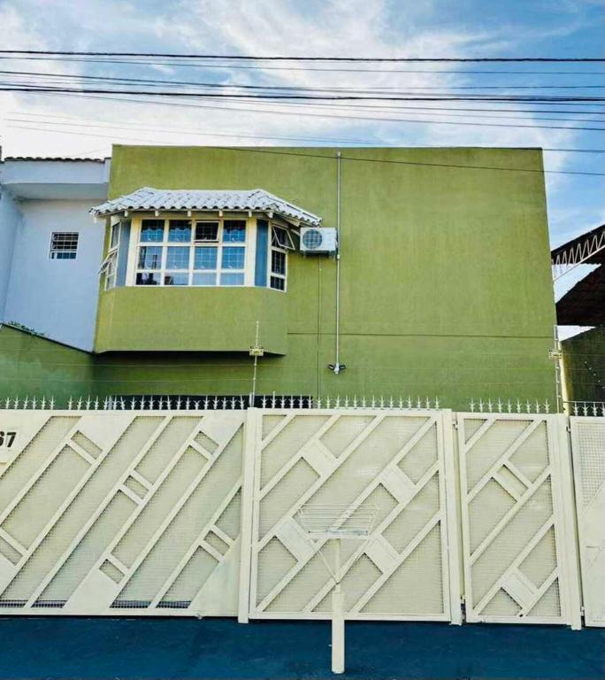 a green house with a fence in front of a building at Hostel Londrina in Londrina